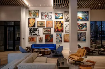 a living room with a large wall of paintings at The Glenmark, Glendale, a Tribute Portfolio Hotel in Glendale