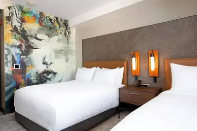 a hotel room with two beds and a painting at The Glenmark, Glendale, a Tribute Portfolio Hotel in Glendale
