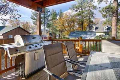 a grill on a deck with chairs and a table at Luxury Lodge-1888 by Big Bear Vacations in Big Bear Lake