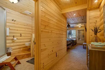 a log cabin bathroom with wooden walls and a bed at Woodland Log-1887 by Big Bear Vacations in Big Bear Lake