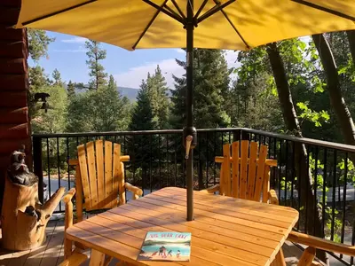 a wooden table with an umbrella on a balcony at Woodland Log-1887 by Big Bear Vacations in Big Bear Lake