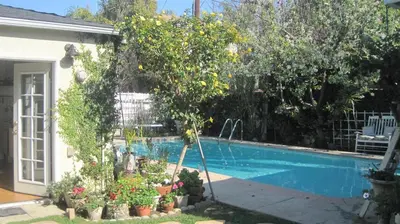 a swimming pool with a lemon tree next to a house at Culver City Escape with Pool, Near Disneyland Park! in Los Angeles