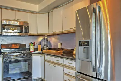 a kitchen with white cabinets and a stainless steel refrigerator at Unique Long Beach House with Patio, Grill and Balcony in Long Beach