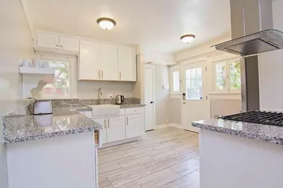 a kitchen with white cabinets and marble counter tops at Hollywood's Garden Paradise at World Artists Living in Los Angeles