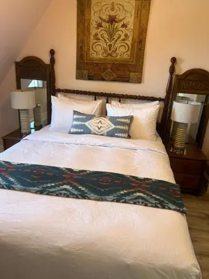 a bedroom with a bed with pillows and a painting on the wall at Arrowhead Lake Inn in Lake Arrowhead