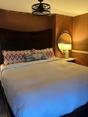 a bedroom with a large white bed with a mirror at Arrowhead Lake Inn in Lake Arrowhead