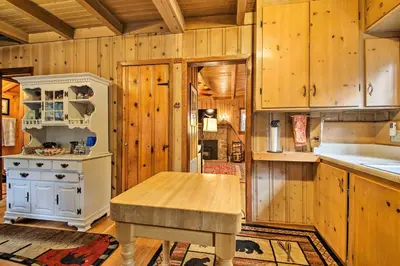 a kitchen with wooden cabinets and a wooden table at Vintage Snow White Cottage about 2 Miles to Village! in Lake Arrowhead