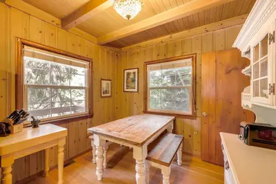 a kitchen with a wooden table and two windows at Vintage Snow White Cottage about 2 Miles to Village! in Lake Arrowhead