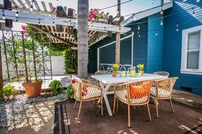a patio with a table and chairs and a blue house at Newly Renovated Gem Mins to Convention Center, Beaches and Downtown LB A in Long Beach