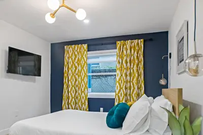 a bedroom with a bed with yellow curtains and a window at Newly Renovated Gem Mins to Convention Center, Beaches and Downtown LB A in Long Beach