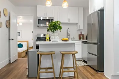 a kitchen with white cabinets and bar stools at Newly Renovated Gem Mins to Convention Center, Beaches and Downtown LB A in Long Beach