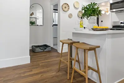 a kitchen with white countertops and wooden stools at Newly Renovated Gem Mins to Convention Center, Beaches and Downtown LB A in Long Beach
