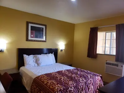 a hotel room with a bed and two windows at Providencia Motel in Burbank