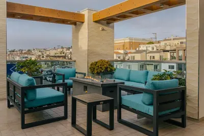a patio with blue chairs and tables on a balcony at H2O Hermosa Beach Hotel in Hermosa Beach