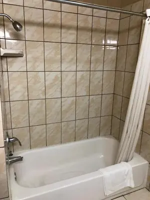 a white bath tub in a tiled bathroom at Aqua Inn Motel in El Monte