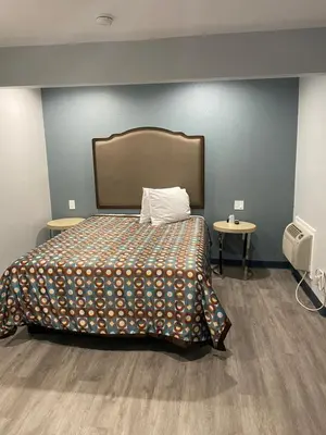 a bedroom with a bed with a blanket and a table at Motel 66 Los Angeles in Los Angeles