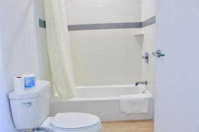 a bathroom with a white toilet and a bath tub at Arlington Motel in Long Beach