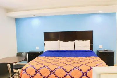 a bedroom with a bed and a blue wall at Arlington Motel in Long Beach