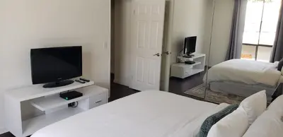 a living room with a bed and a tv on a stand at Skyline Views 1-Bedroom with Balcony and Pool in Los Angeles