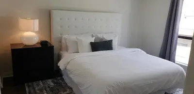 a bedroom with a white bed and a lamp at Skyline Views 1-Bedroom with Balcony and Pool in Los Angeles