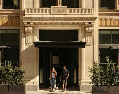 a man and woman walking a dog in front of a building at The Hoxton, Downtown LA in Los Angeles