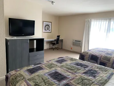 a hotel room with a bed and a flat screen tv at Apple Valley Hotel & Lodge in Apple Valley