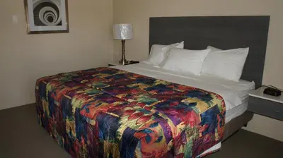 a bed in a hotel room with a colorful blanket at Apple Valley Hotel & Lodge in Apple Valley