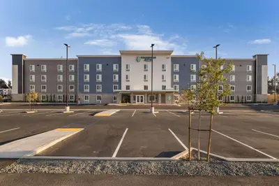 an empty parking lot in front of a large building at WoodSpring Suites Colton in Colton