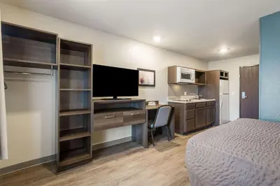 a hotel room with a bed and a desk with a television at WoodSpring Suites Colton in Colton