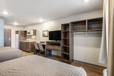 a hotel room with two beds and a desk and a kitchen at WoodSpring Suites Colton in Colton