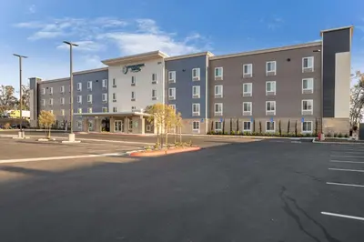 an empty parking lot in front of a large building at WoodSpring Suites Colton in Colton