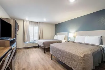 a hotel room with two beds and a flat screen tv at WoodSpring Suites Colton in Colton