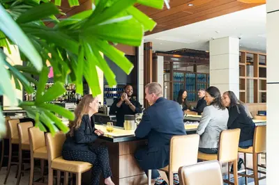 a group of people sitting at a bar in a restaurant at Luskin Hotel in Los Angeles