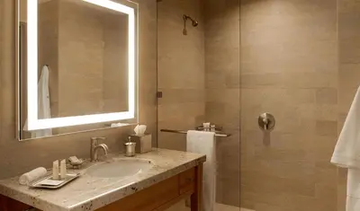 a bathroom with a sink and a shower with a mirror at Luskin Hotel in Los Angeles