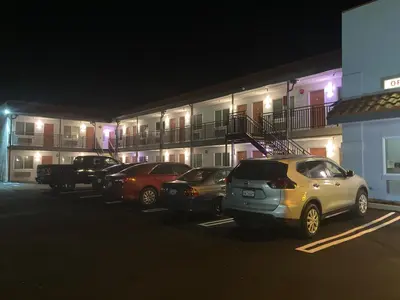 a row of cars parked in a parking lot in front of a building at PASADENA LODGE in Pasadena