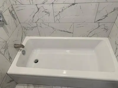 a white bath tub in a bathroom with marble walls at Travel Inn Motel in Anaheim