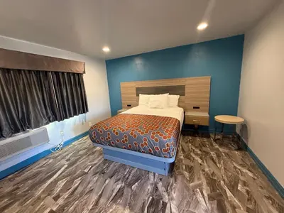 a bedroom with a bed and a blue wall at Travel Inn Motel in Anaheim