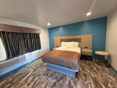 a bedroom with a bed and a blue wall at Travel Inn Motel in Anaheim