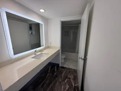 a bathroom with a sink and a mirror and a toilet at Travel Inn Motel in Anaheim