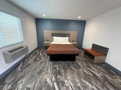 a bedroom with a bed and a large window at Travel Inn Motel in Anaheim