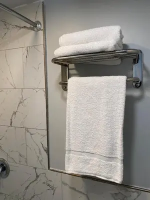 a bathroom with white towels on a towel rack at Travel Inn Motel in Anaheim