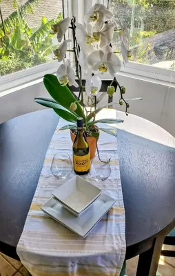 a table with a bottle of wine and a vase with flowers at Top Location Walk to Dining, Shops & Near Beach CC E in Culver City