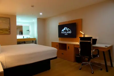 a bedroom with a bed and a desk with a computer at Highland Inn - San Bernardino in Highland