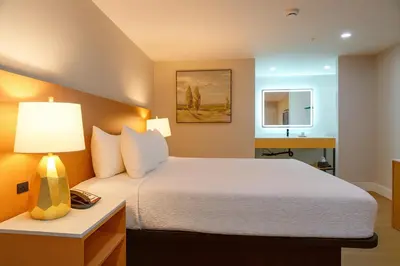 a bedroom with a bed with a lamp and a mirror at Highland Inn - San Bernardino in Highland