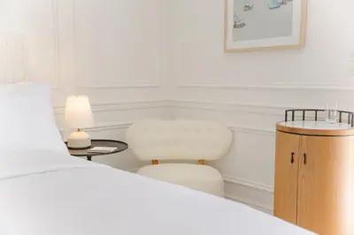 a bedroom with a white bed and a chair at Cara Hotel in Los Angeles