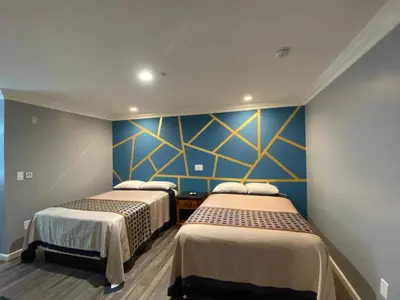 two beds in a room with blue walls at ERTH INN by AGA Maywood in Maywood