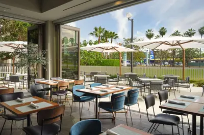 a restaurant with tables and chairs and umbrellas at Hyatt House LAX Century Blvd in Los Angeles