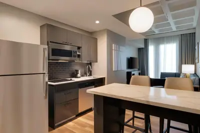 a kitchen with a refrigerator and a table with chairs at Hyatt House LAX Century Blvd in Los Angeles