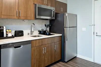a kitchen with wooden cabinets and a stainless steel refrigerator at Staybridge Suites - Long Beach Airport by IHG in Long Beach
