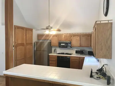 a kitchen with wooden cabinets and a stainless steel refrigerator at Quail Run Cabin 4,000 Sq.Ft Largest & Most Beautiful House On The Mountain in Pine Mountain Club